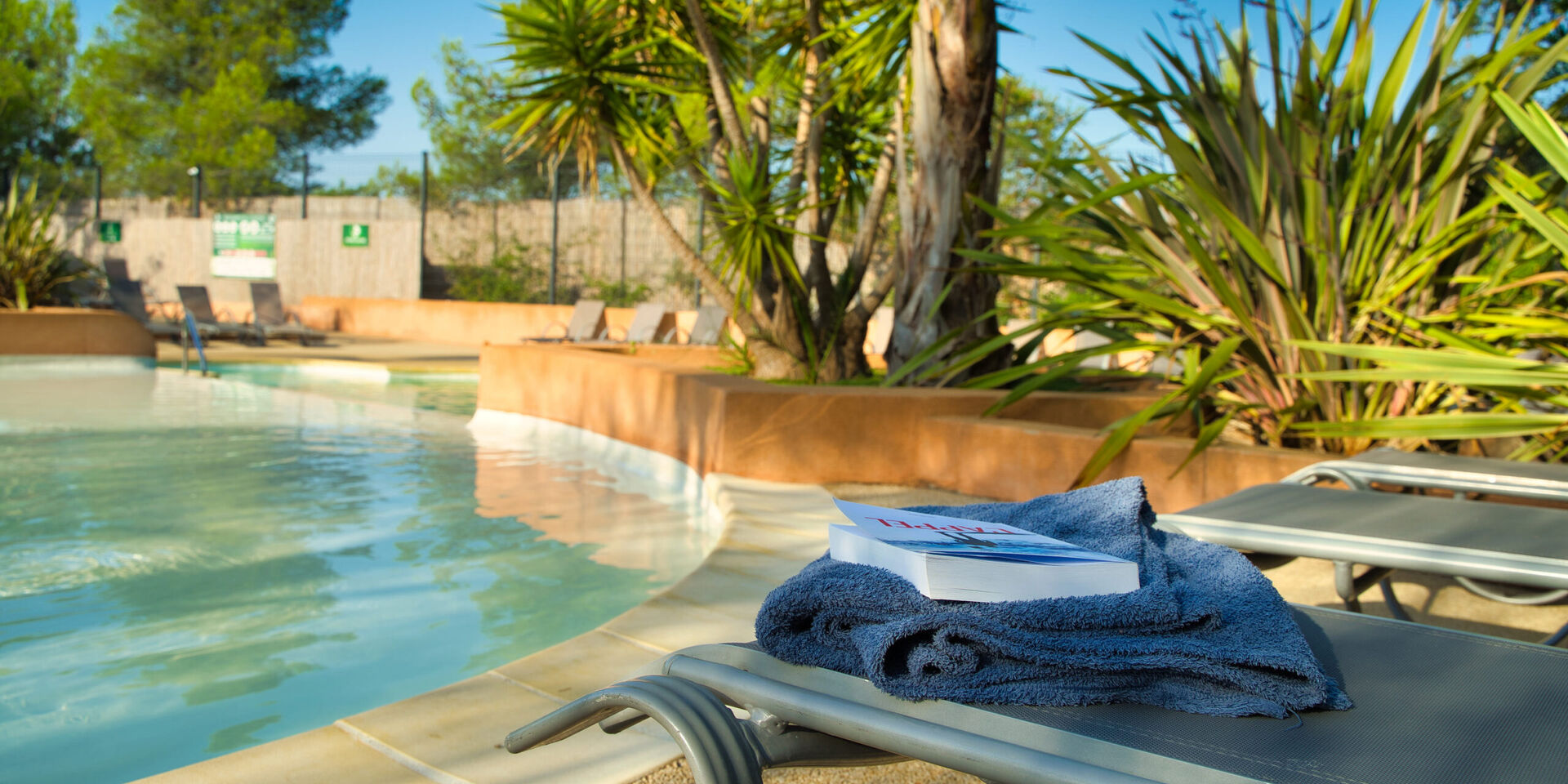 Transat en bord de piscine : lecture au calme et à l'ombre